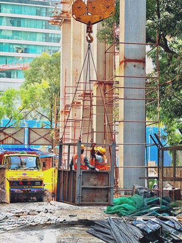 Construction workers riding a crane-lifted platform on a high-rise site